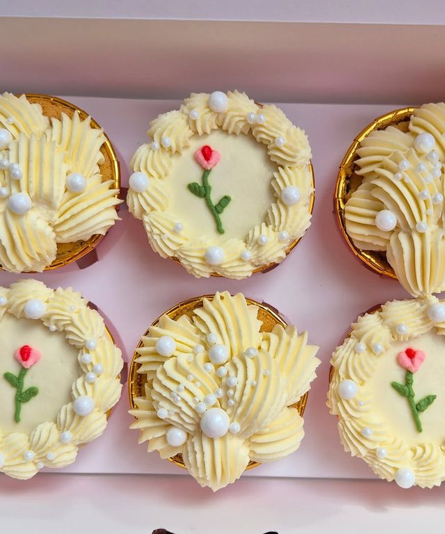 Cupcakes ivoire ornés de couronnes de crème, de perles et d'une petite rose