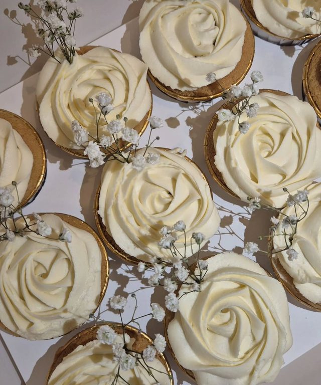 Cupcakes aux rosaces ivoire décorés de gypsophile sur des caissettes dorées