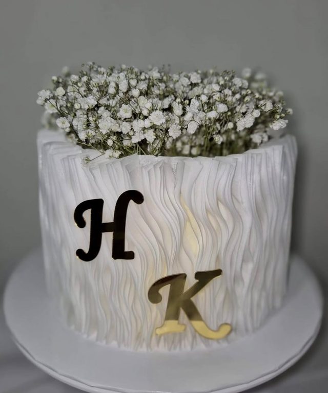 Layer cake blanc à volants décoré de gypsophile et des lettres H et K