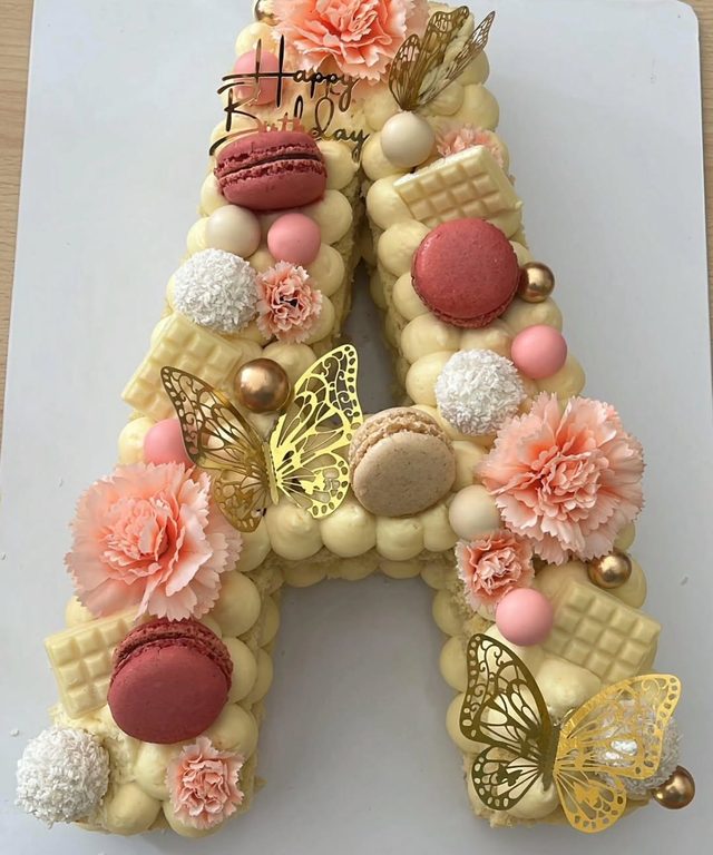 Letter cake en forme de A, macarons, fleurs et papillons dorés